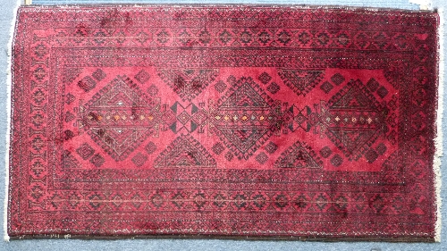 Tribal rugs; an Afghan rug with three central guls on a red ground set within a wide geometric