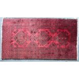 Tribal rugs; an Afghan rug with three central guls on a red ground set within a wide geometric