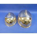 A graduated pair of silver plated Meat Domes, of ovoid form chased with floral swags and demi-fluted