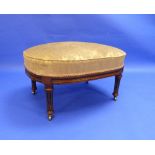 An Edwardian walnut framed oval Stool, with overstuffed yellow floral upholstery, raised on reeded