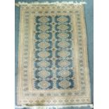 Tribal rugs; a blue ground Bokhara rug with cream, gold and blue tekke set within a wide border,