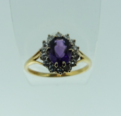 A cluster Ring, set with an oval amethyst, with fourteen small diamonds around, and mounted in 750