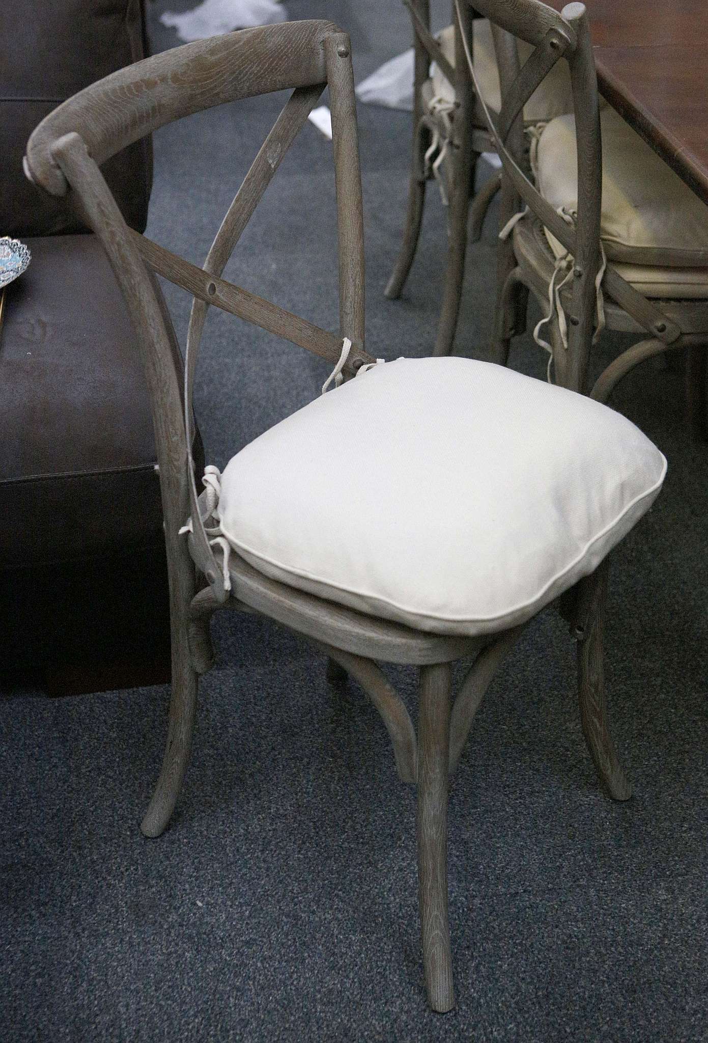 A set of six grey painted dining chairs with squab cushions on a splayed circular section legs.