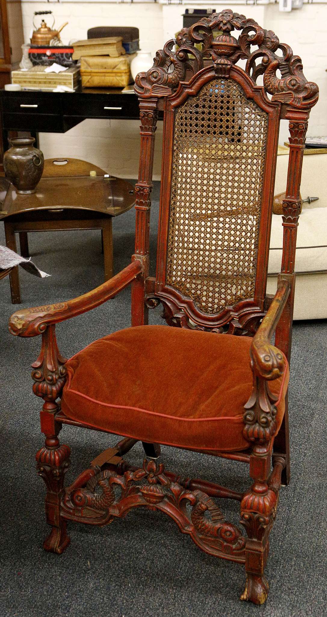 A mid 19th century elbow chair, carolean design, red finish, dolphin, urn and floral carved