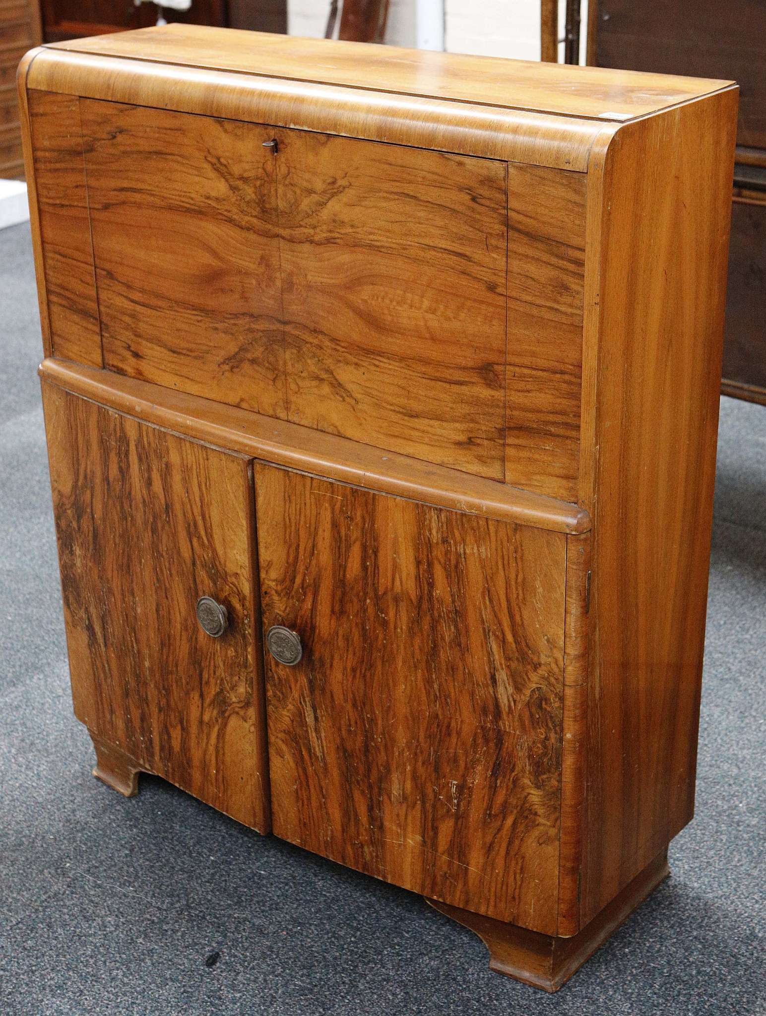 A 20th century Art Deco figured walnut, fall front bureau over a bow fronted cabinet, raised on