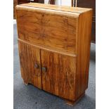 A 20th century Art Deco figured walnut, fall front bureau over a bow fronted cabinet, raised on