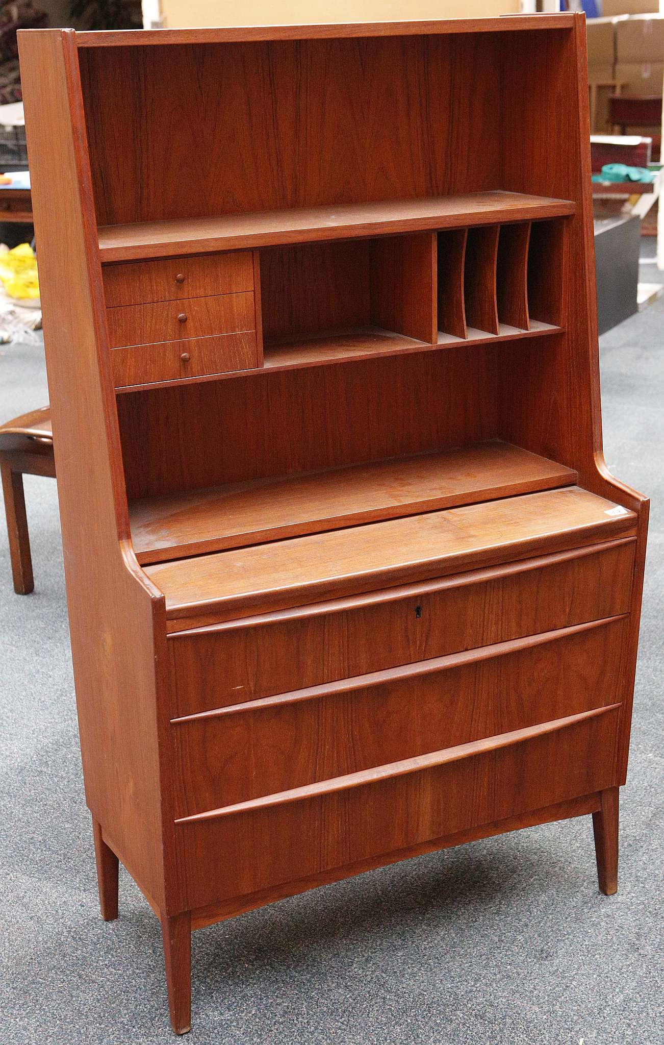 A Danish teak escritoire housing small 'nooks' and drawers over three long drawer. 84 x 42 x 142cm.