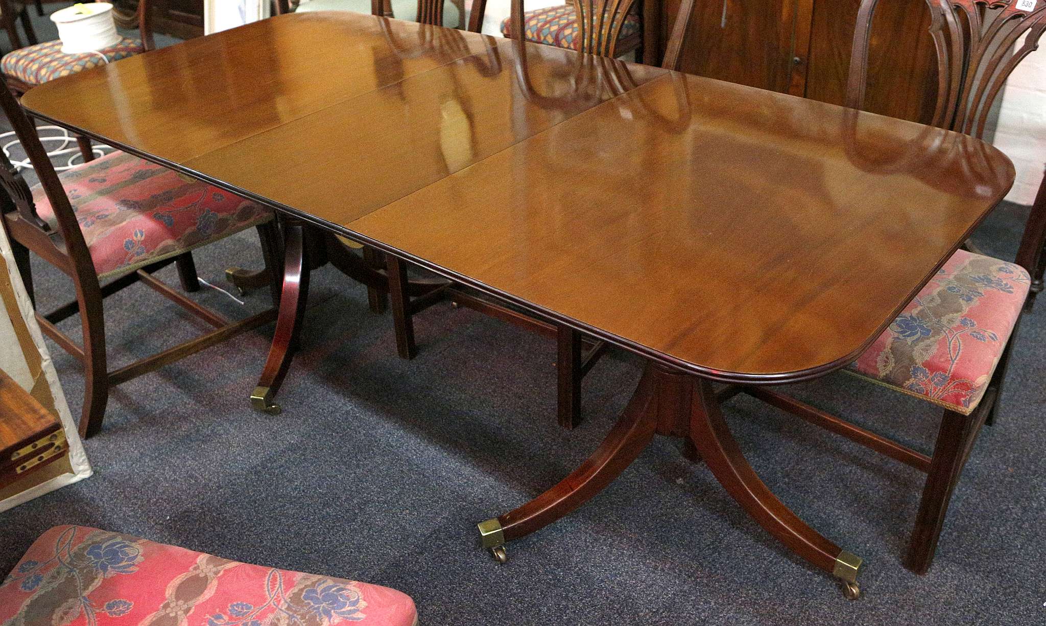 A mahogany twin pedestal dining table by A. McEwan, the tripod pedestals with splayed legs on