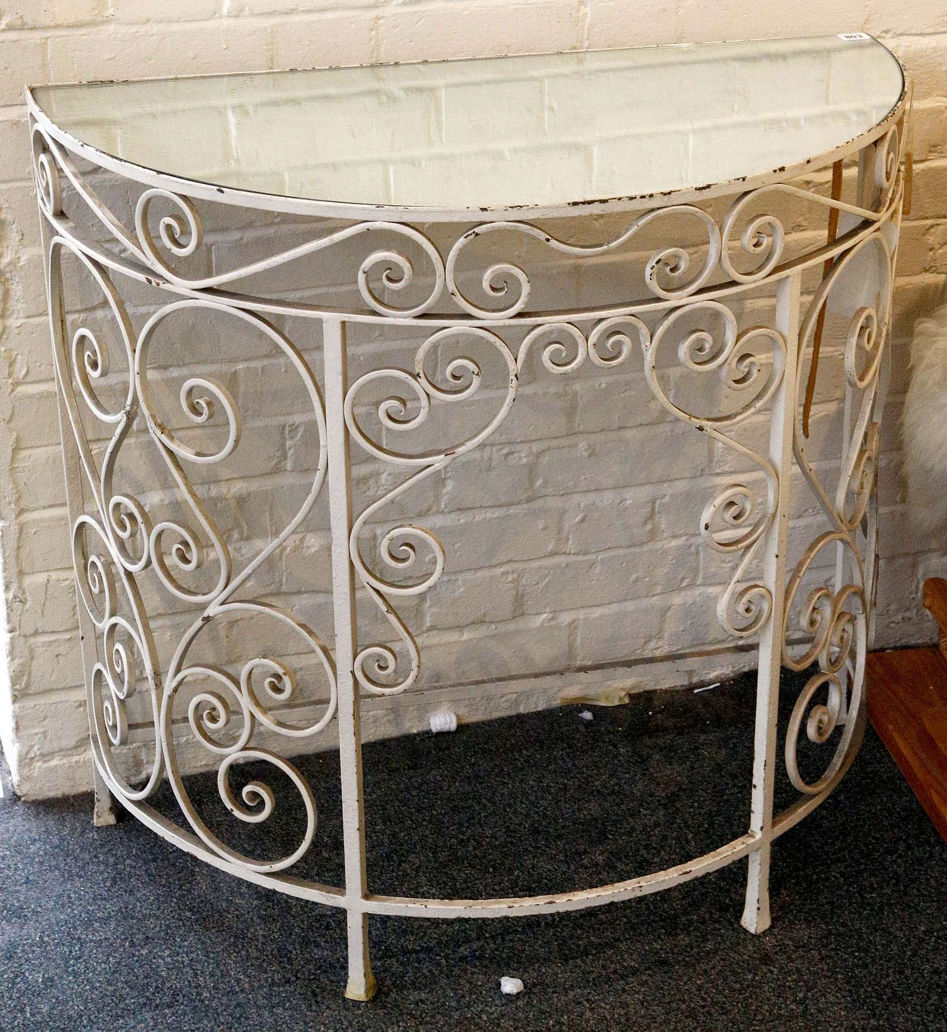 A demi-lune mirrored topped console table raised on scrolling cast iron supports. 90 x 45 x 85cm.