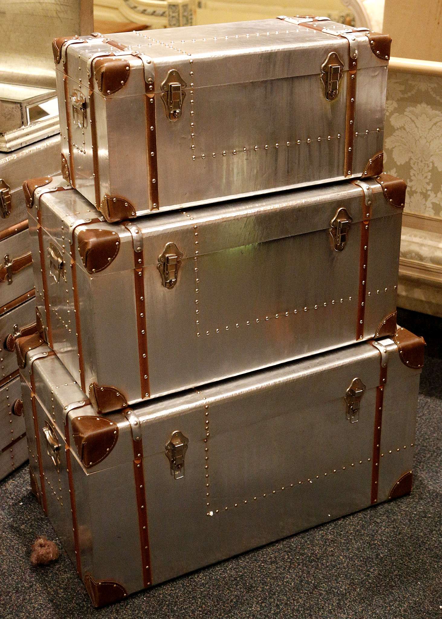 A set of three aluminium, graduated aviation chests with a leather and rivet trim, largest 80 x 45 x