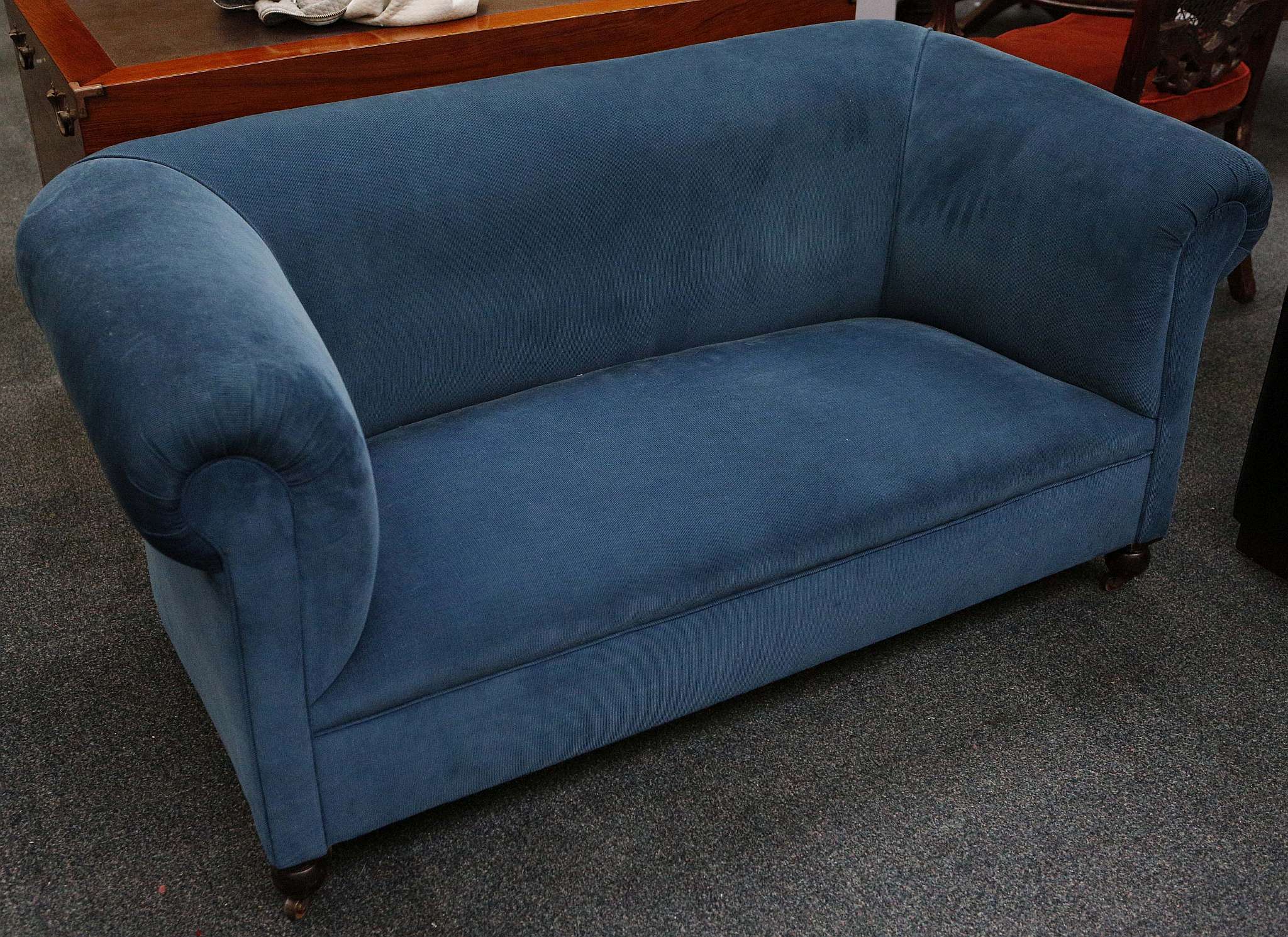 An Edwardian blue velvet upholstered sofa, raised on bun feet.