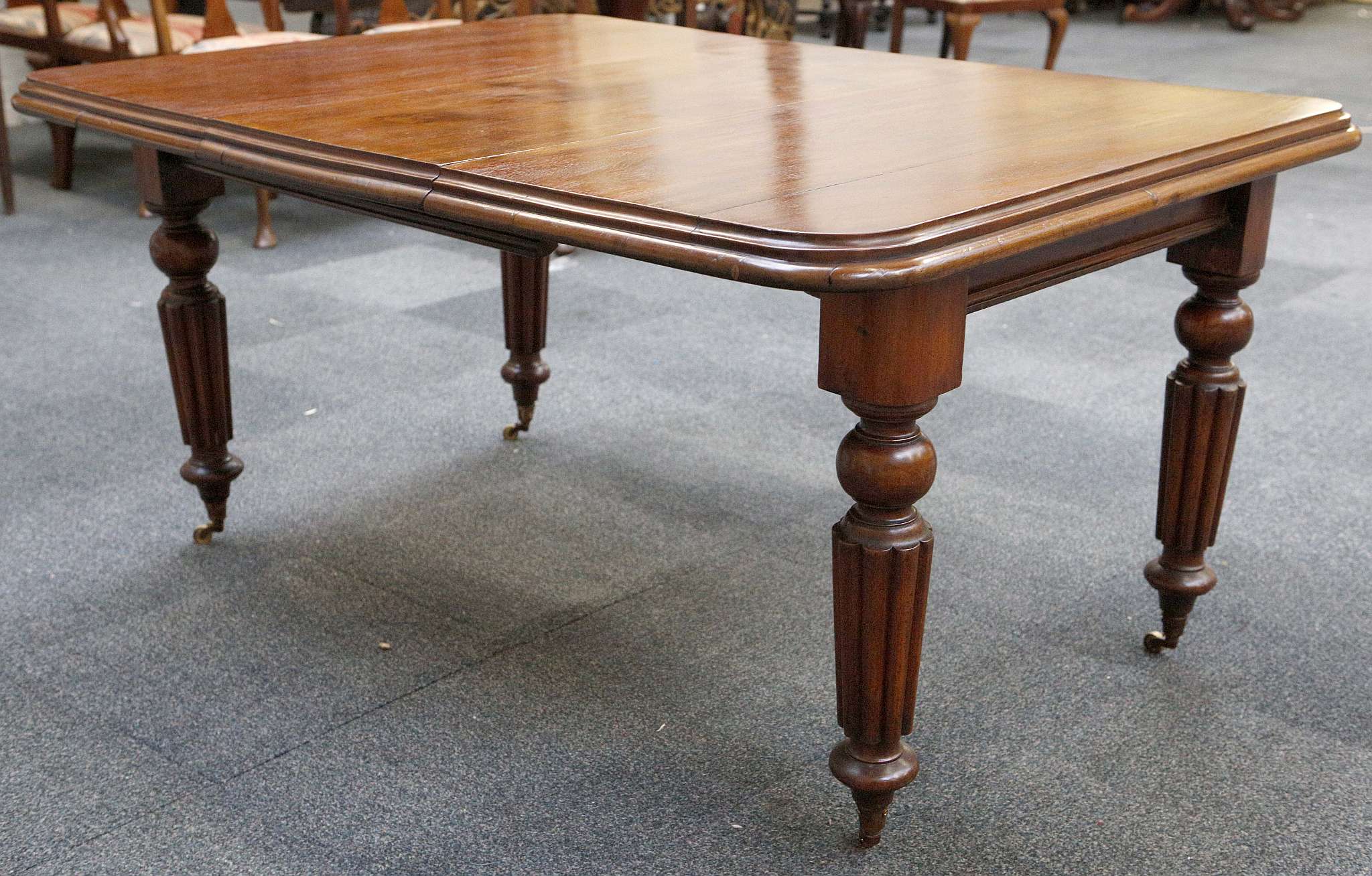 A Victorian wind out dining table, mahogany, rounded corners, tapering turned and reeded legs, brass