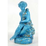 A blue porcelain figure in the style of Sevres, of a young girl seated on a rocky outcrop,