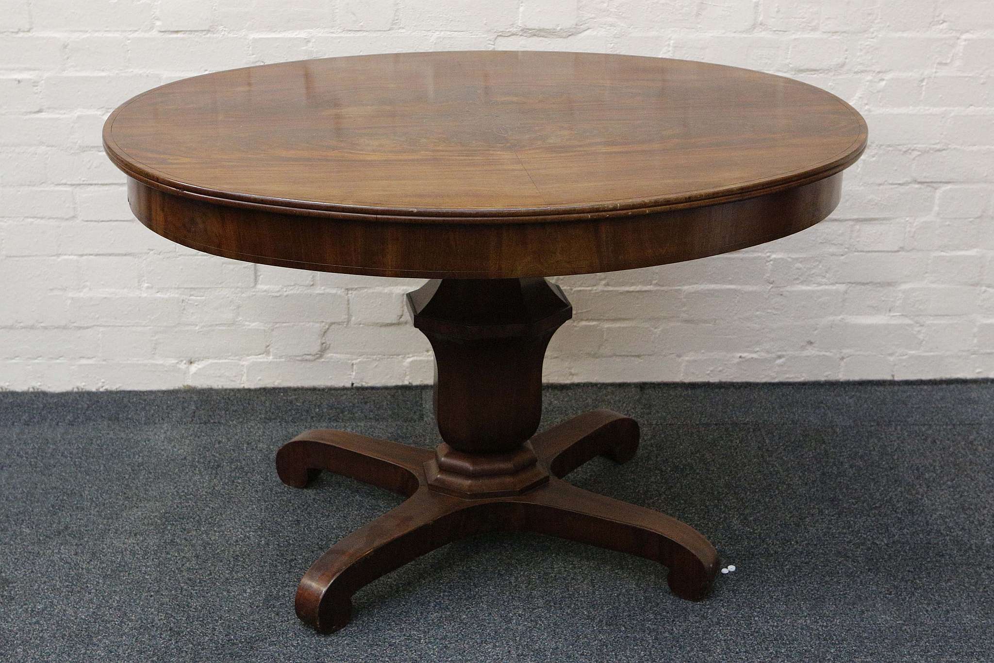 A Victorian oval centre table, flame mahogany with inlaid brass leaf detail, urn stem, quadripartite