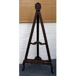An artist's easel, oak stain, scallop surmount, carving to tray and feet. 180cm high.