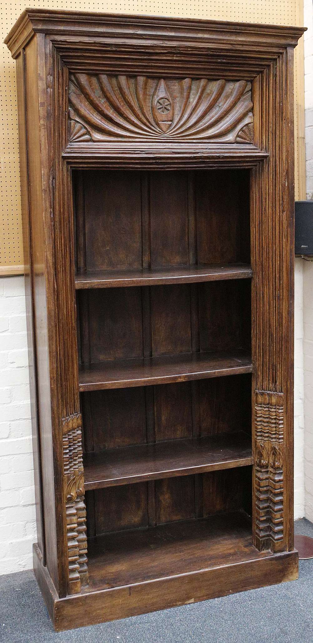 A contemporary carved Indian hardwood floor standing bookcase,  four open shelves, raised on a