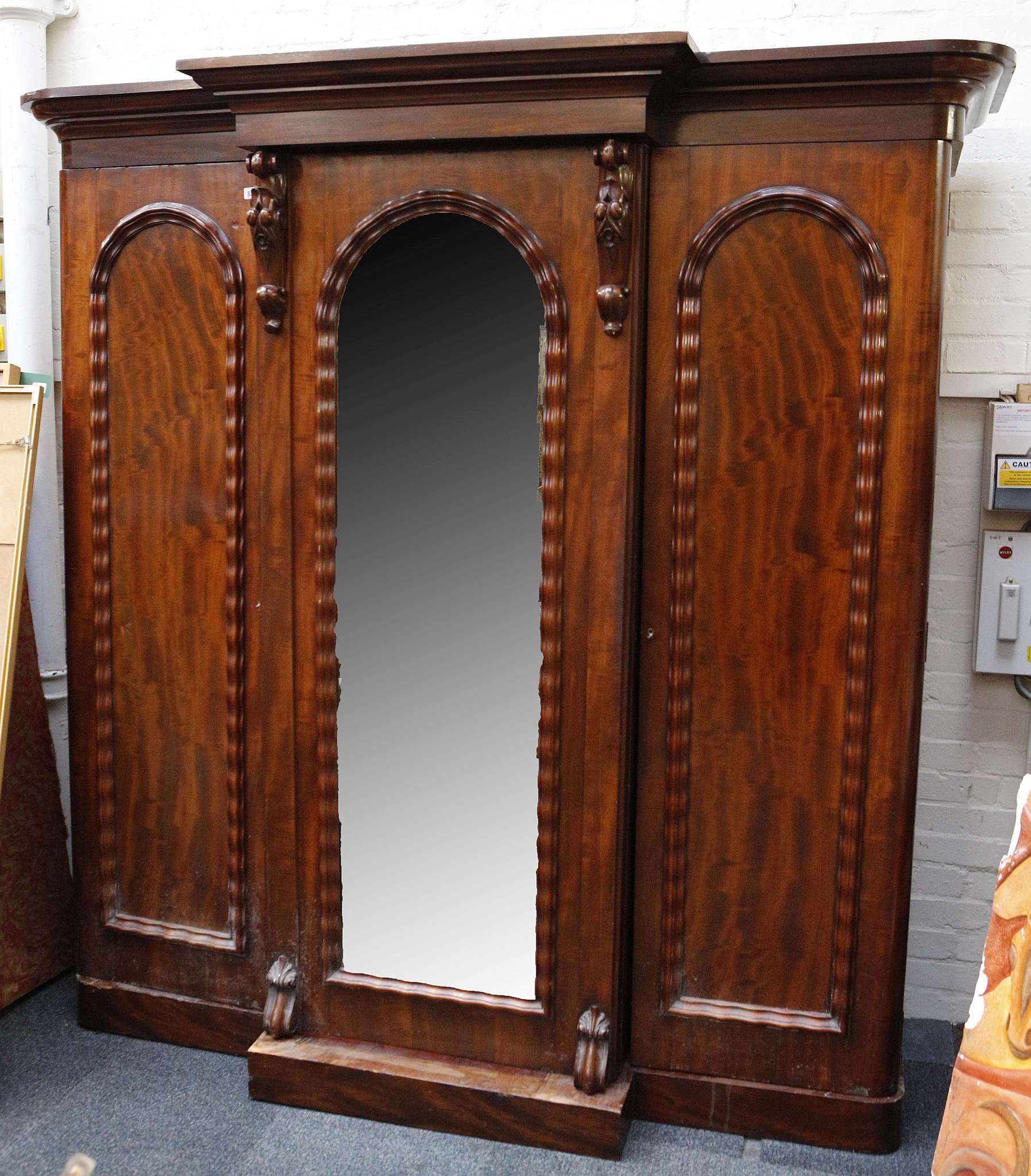 A late Victorian triple wardrobe, flame mahogany, wave beading, applied floral mounts, hanging units