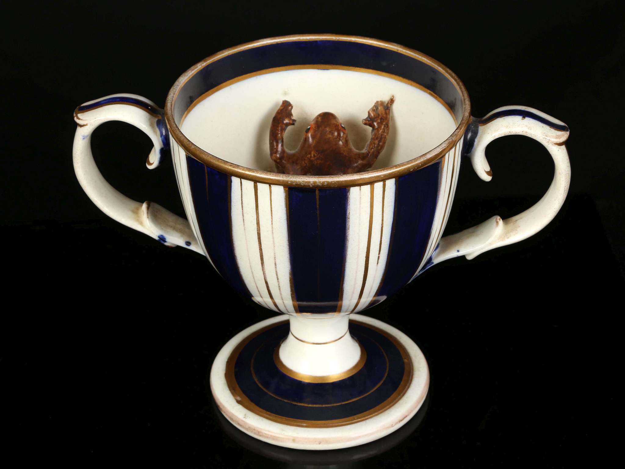 A CHARMING ENGLISH CREAMWARE LOVING CUP WITH A FROG, circa 1830, the cup-shaped form with a brown