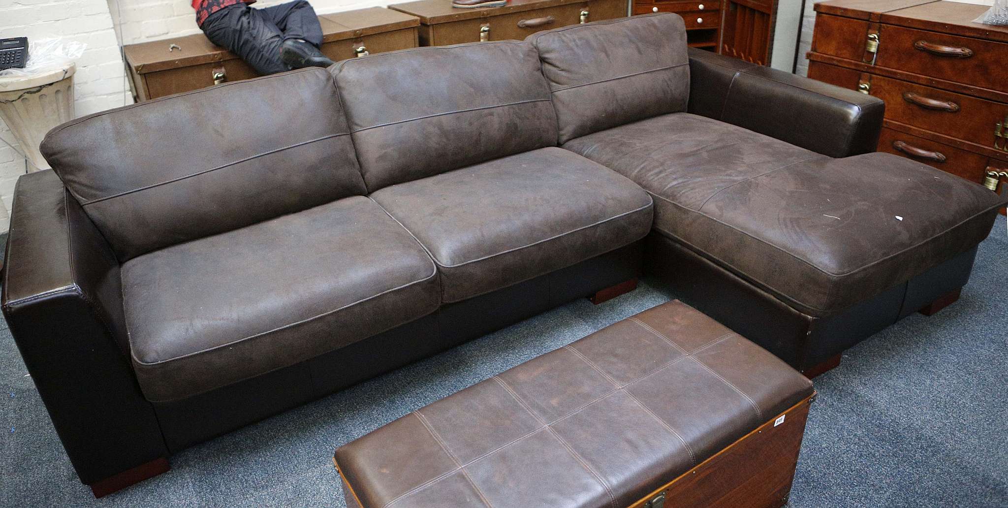 A brown leather corner unit with brown suede cushions, raised on block feet.