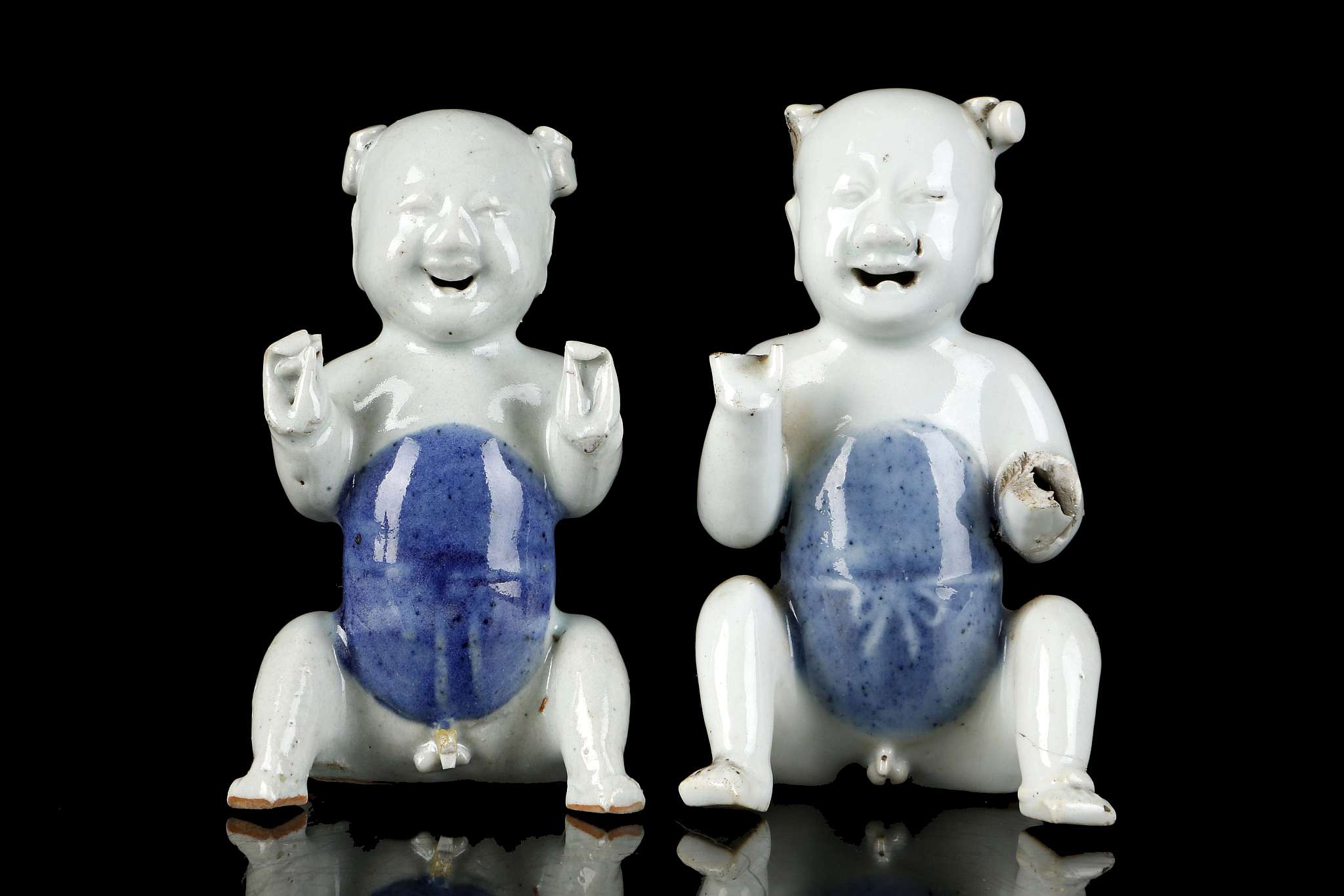 A PAIR OF CHINESE PORCELAIN MODELS OF SEATED BOYS.