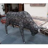 A distressed metal garden ornament of a raging bull with a scrolling pierced metal finish and