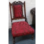 An Edwardian armchair with carved crest over an up