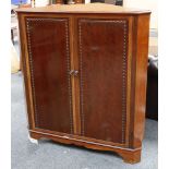 A 20th century mahogany corner unit with a pair of doors with rope twist decoration, opening to