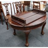 An Edwardian walnut oval extending dining table, with graduated edge, raised on carved cabriole legs