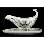 A CHINESE FAMILLE VERTE SAUCEBOAT AND ATTACHED STAND.
Late Qing Dynasty.
The exterior of the oval