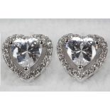 A pair of heart shaped silver earrings set with cu