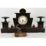 An Edwardian Belgian slate and red marble clock garniture, having a shaped clock case and matching