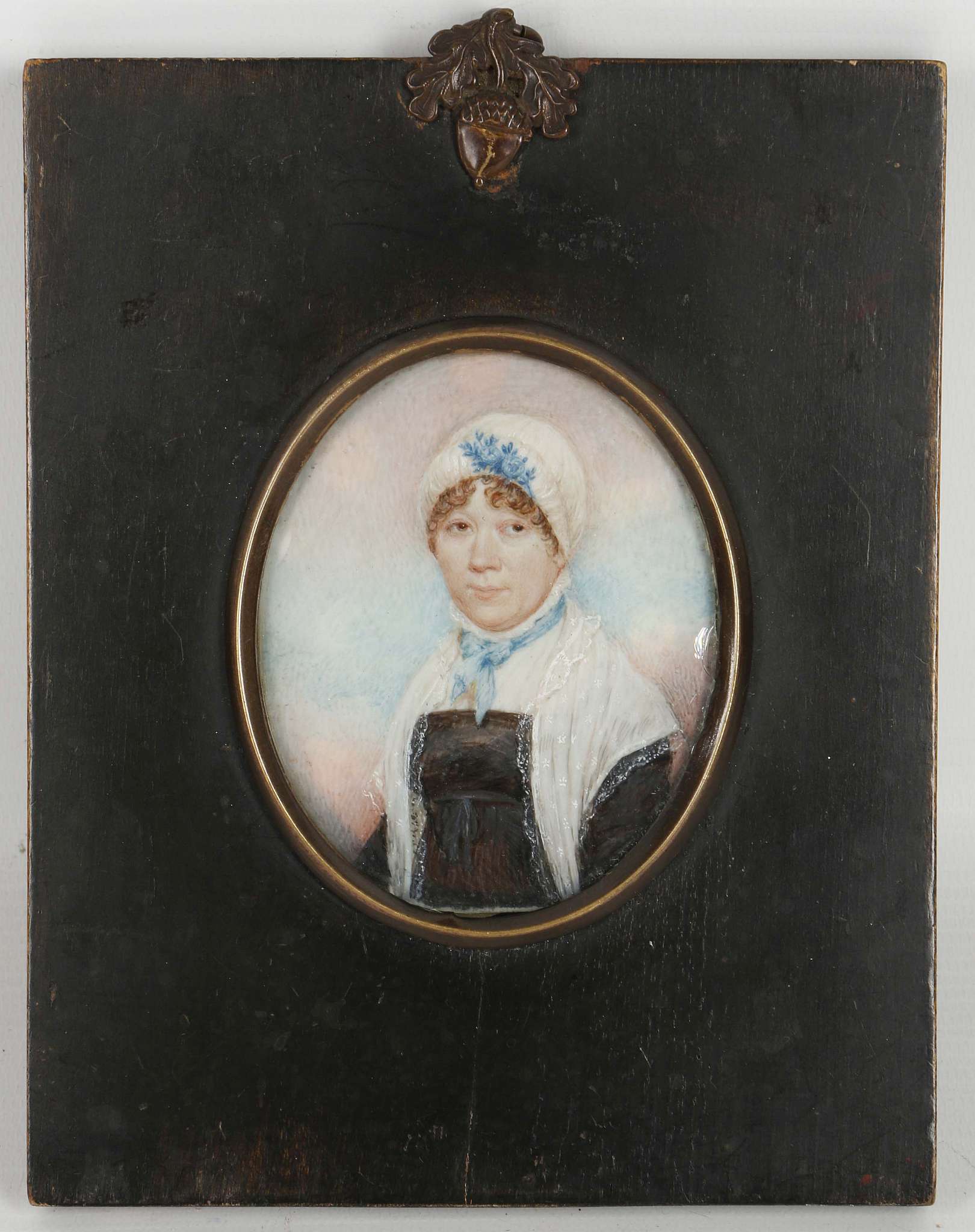 A mounted portrait miniature of a lady in a black dress.