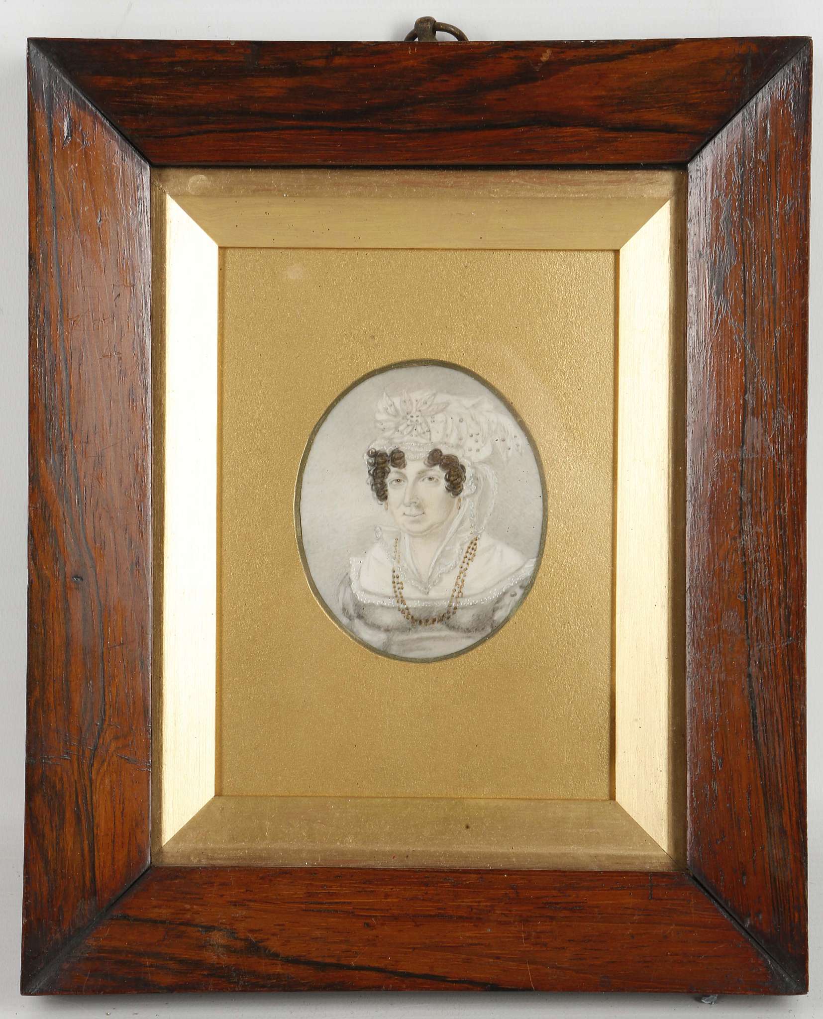 A mounted portrait miniature of a lady in grey dress with pearls.