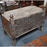 An Eastern carved softwood chest, late 19th century. The divided hinged lid above an entwined