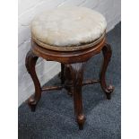 A Victorian walnut upholstered circular topped, height adjustable piano stool, on carved cabriole