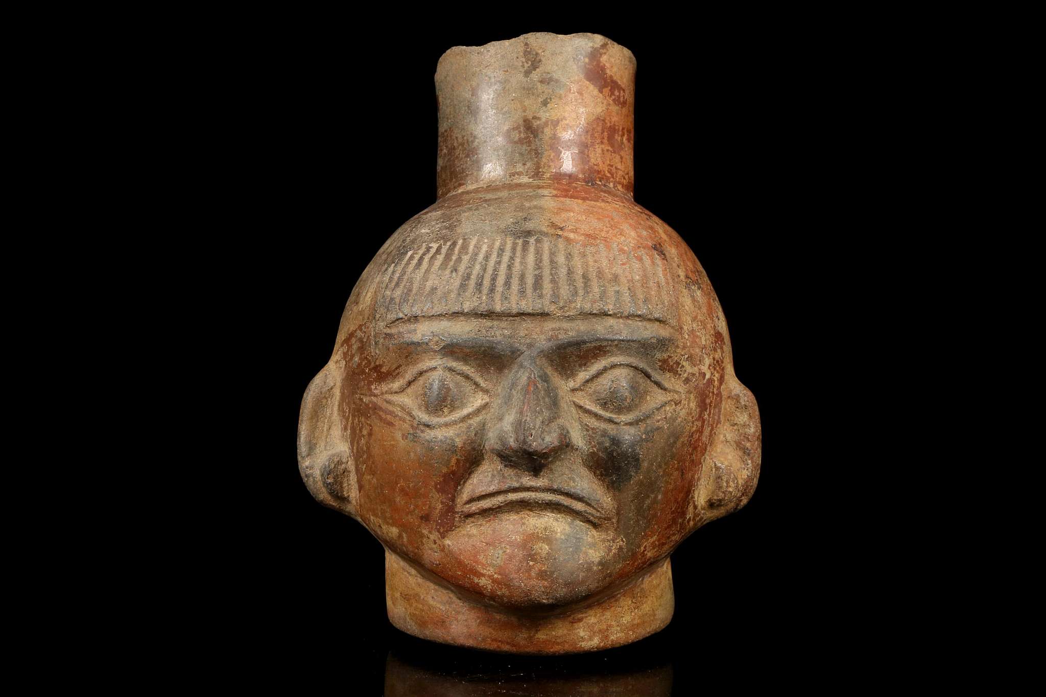 A MOCHE HEAD VESSEL, PERU Depicting the head of a man, possibly a priest, with a short fringe over