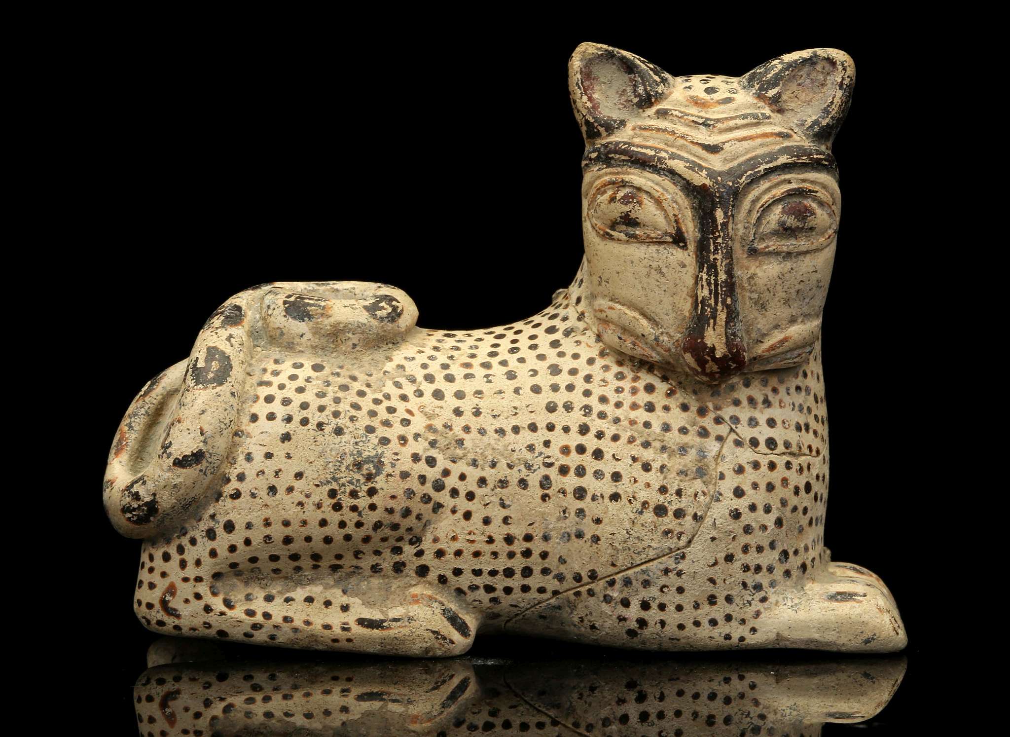 AN ITALO-CORINTHIAN STYLE POTTERY FIGURAL VESSEL In the shape of a crouching lion, the tail curled