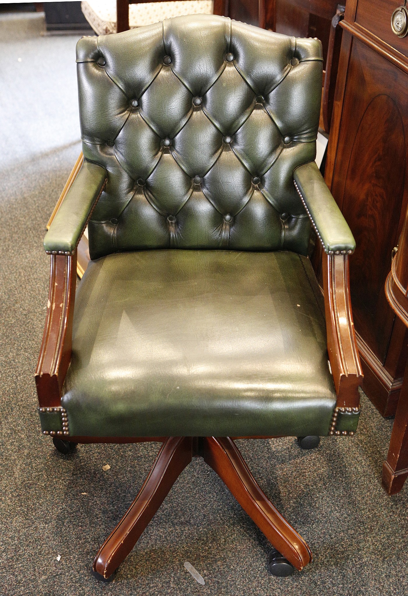 A green leather office chair, with button upholstered back over an upholstered seat flanked by