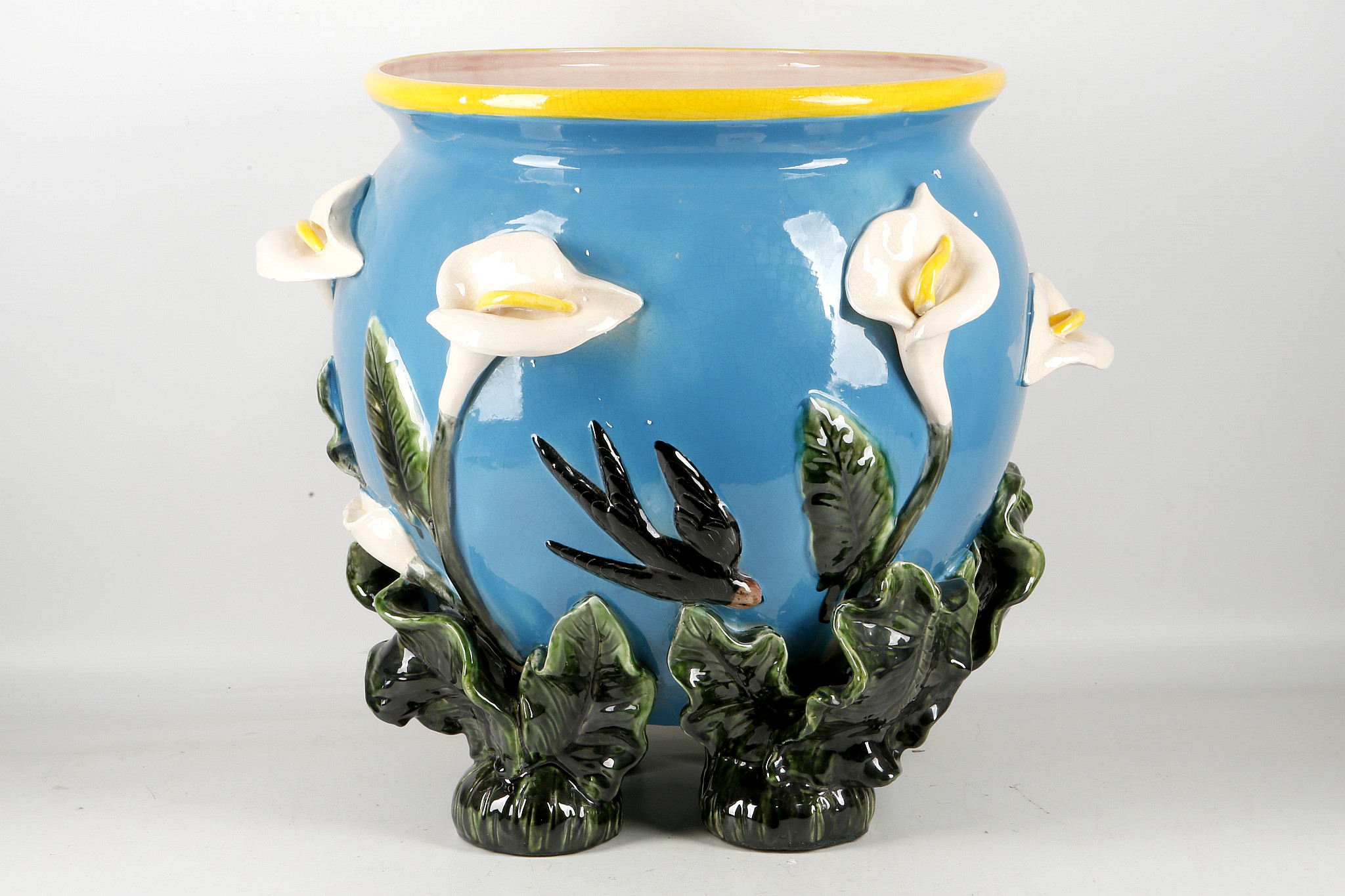 A Majolica style planter, lily and swallow decoration with 'plant' feet, 37cm diameter.