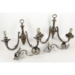 A pair of twin branch scrolling arm wall sconces in neo-classical style, in bright pewter finish.