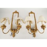 A pair of twin arm girondel wall lights, leaf surmount, ribbon fold trim, clouded mirror, 55cm high