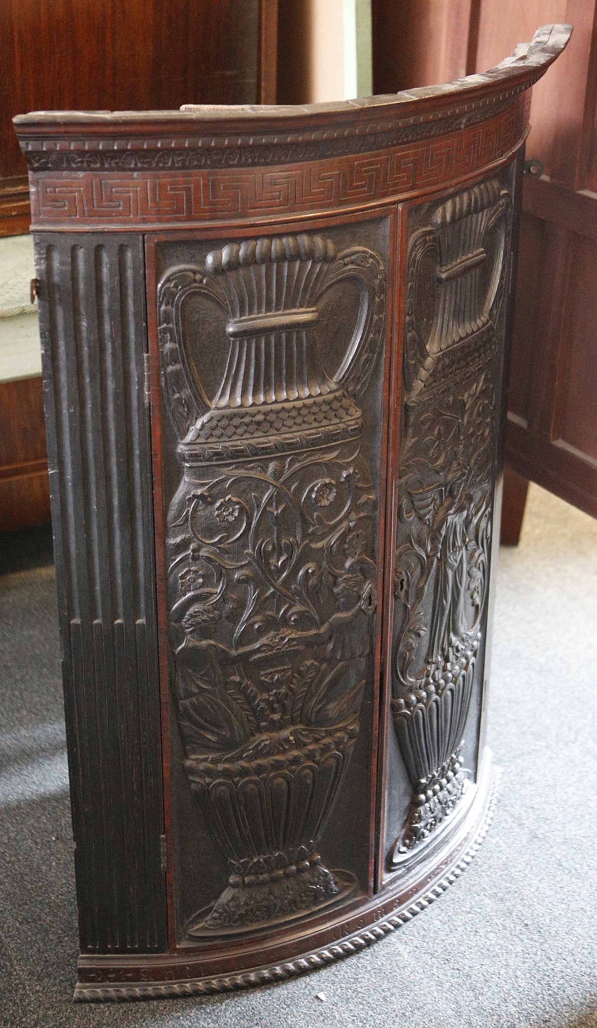 A 19th century corner cabinet, heavily carved bow oak panel doors with classical scenes, reed