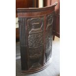 A 19th century corner cabinet, heavily carved bow oak panel doors with classical scenes, reed