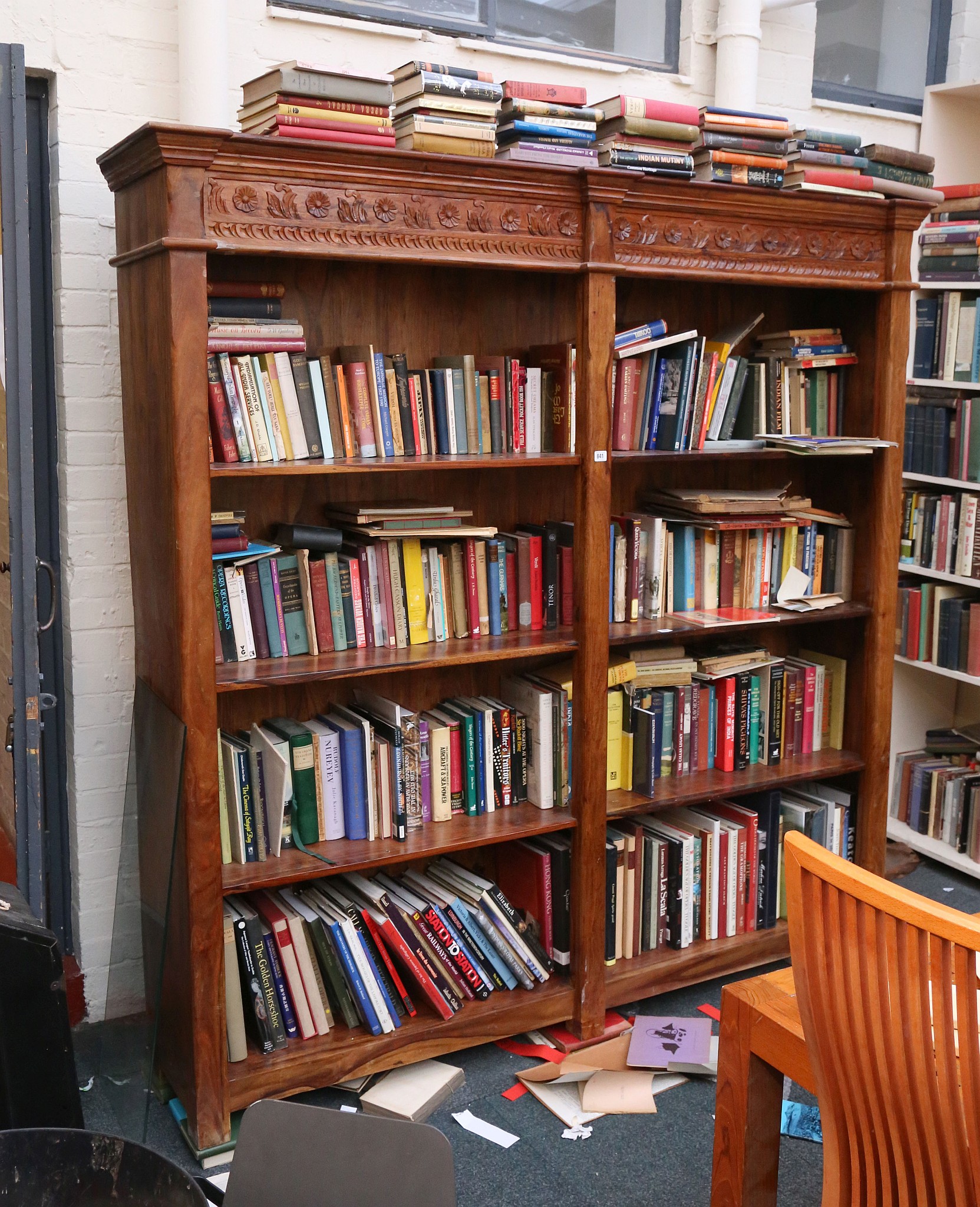 A 20th century, double front set of open bookcases in tropical hardwood and having a carved top