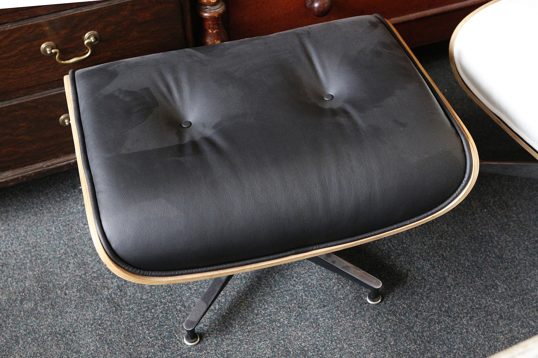 An Eames inspired ottoman, having black faux leather upholstery, raised on chrome base, 41 H x 65