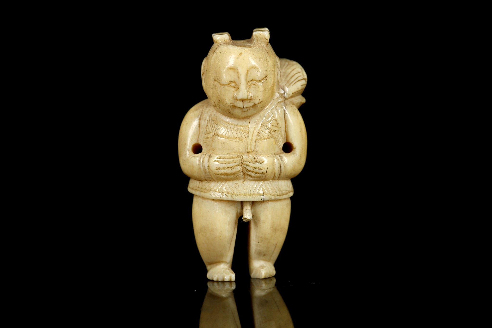 A JAPANESE IVORY NETSUKE FORMED AS A BOY. Meiji Period. Carved standing and holding a lotus