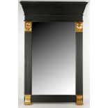 A wall mirror, with ebonised frame and Egyptian masks.