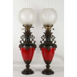 A pair of Victorian oil lamps having black and red bodies with applied bronzed decoration. Each