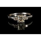 An 18ct white gold and diamond engagement ring, the central princess cut stone flanked by