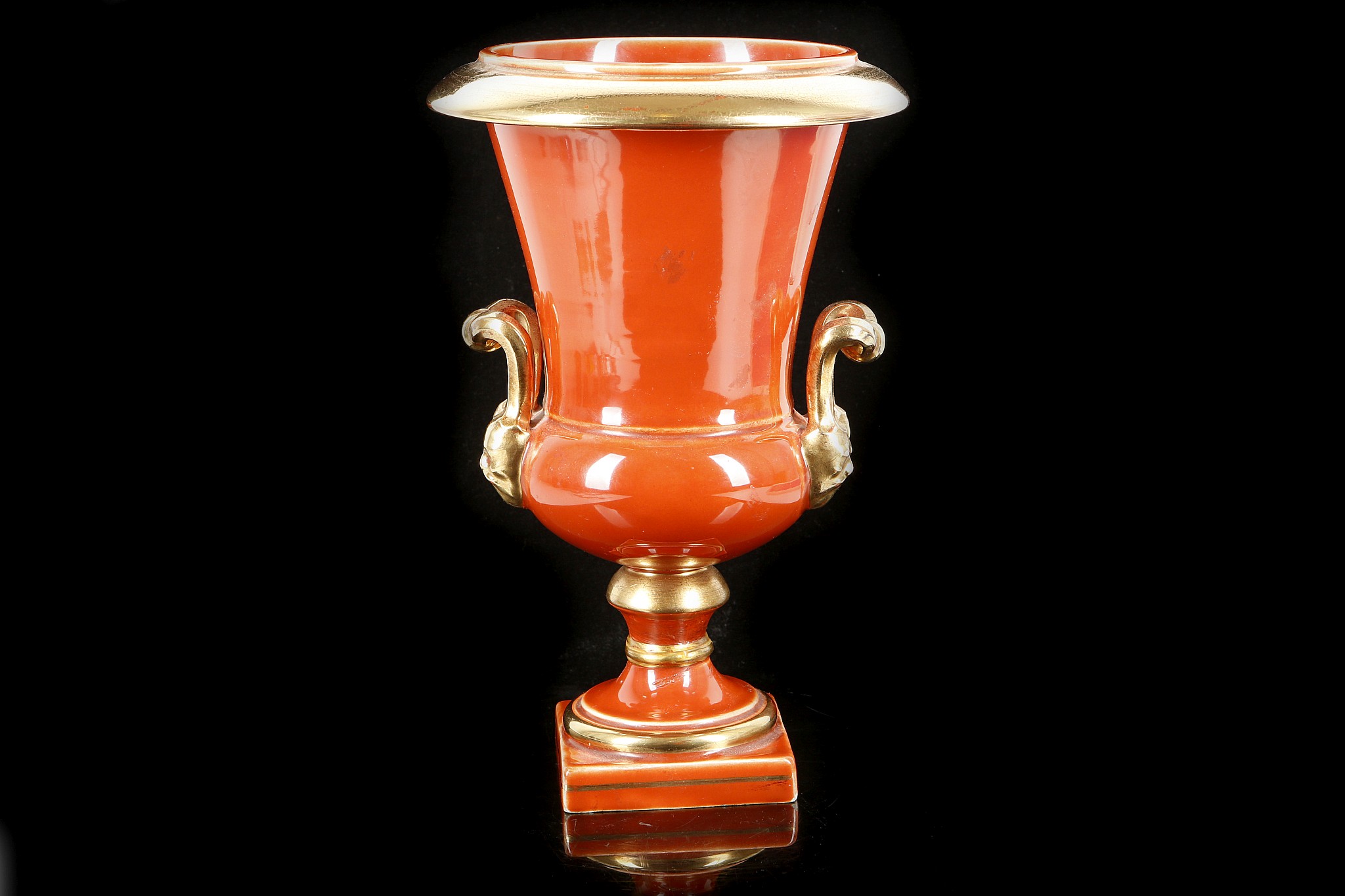 A Sang-de-boeuf glazed inverted campana form ceramic twin handled urn, on socle plinth, with gilt
